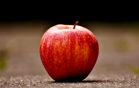 Shallow Focus Photography Of Red Apple On Gray Pavement
