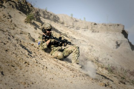 Soldier Man With Black Rifle Sliding On Cliff photo