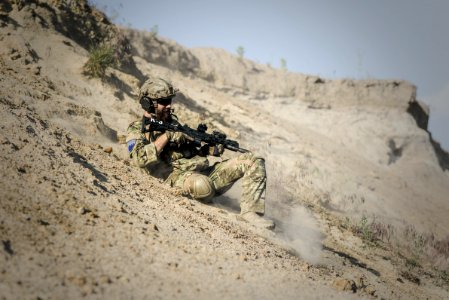 Soldier Man With Black Rifle Sliding On Cliff