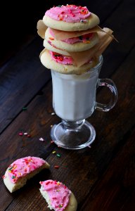 Cookies With Pink Cream On Top Of Clear Short Stem Footed Mug With Milk