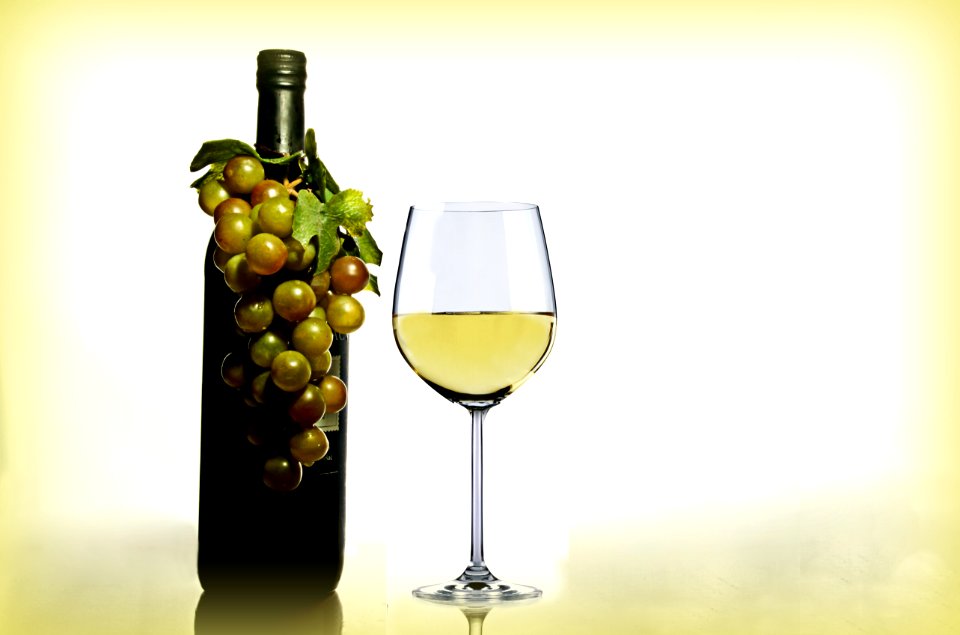 Wine In Wine Glass Near Green Glass Bottle
