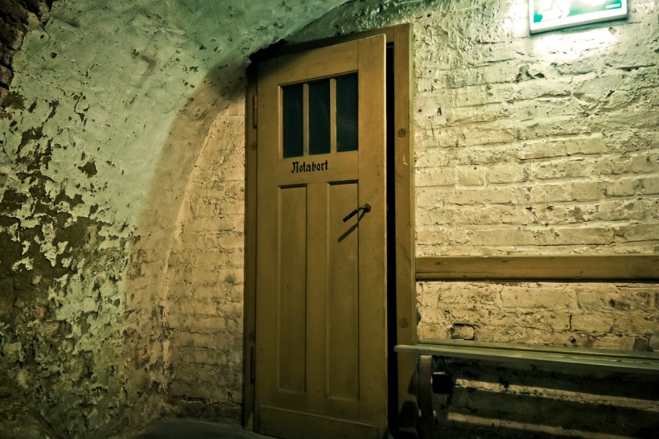 Brown Wooden Door Near White Brick Wall