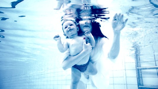 Grayscale Photography Of Woman Holding Baby In Swimming Pool photo