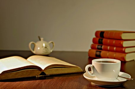 White Ceramic Teacup On Brown Wooden Table Beside Book photo