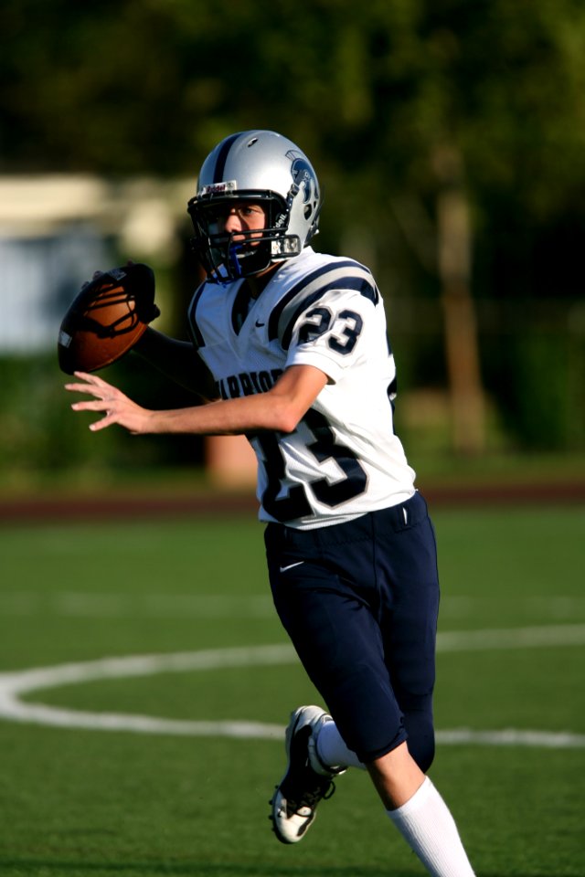 Man In White And Black Football Jersey Playing On Field During Daytime