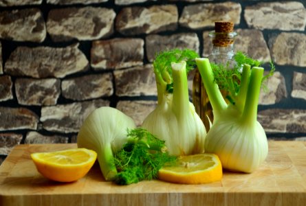 Green And White Onions And Sliced Lemons On A Brown Surface