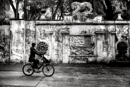 Woman Wearing Jacket And Pants Riding On Bicycle Near Concrete Wall Greyscale Photo photo