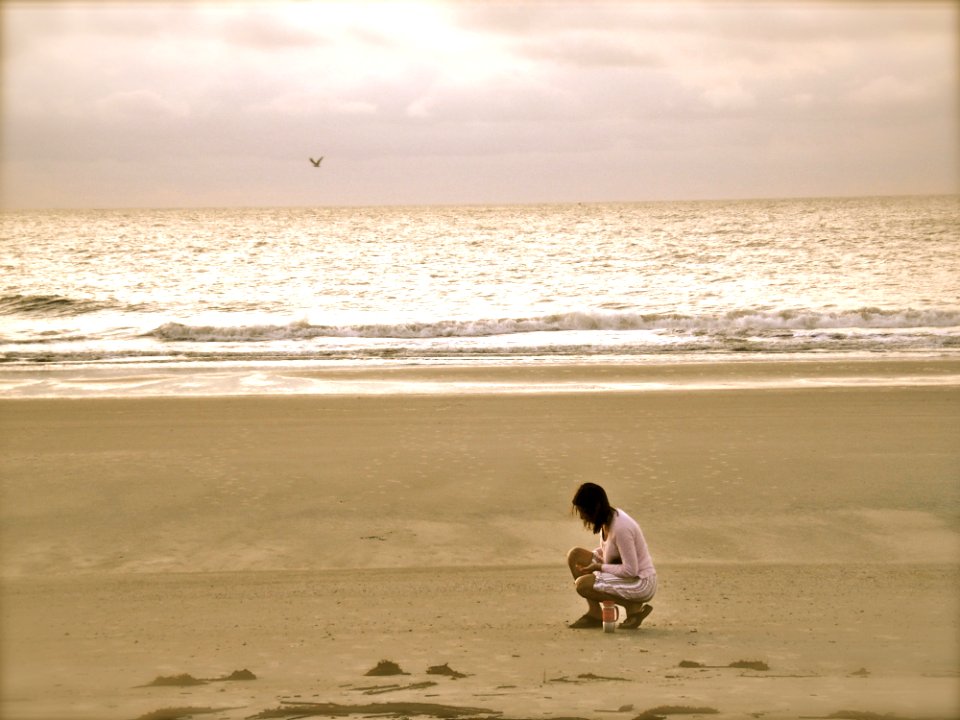 Woman In Pink Cardigan Sitting On Seashore