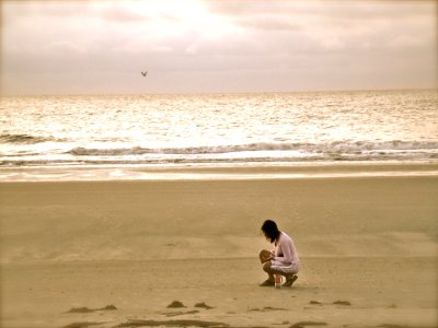 Woman In Pink Cardigan Sitting On Seashore photo