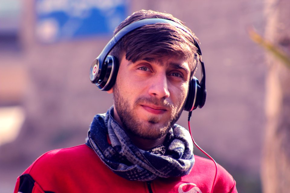 Closeup Photo Of A Man Wearing Red Top Gray Scarf And Black Beats By Dr Dre Headphones