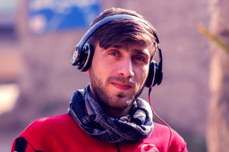 Closeup Photo Of A Man Wearing Red Top Gray Scarf And Black Beats By Dr Dre Headphones photo