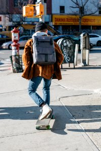 Man Wearing Brown Jacket Blue Denim Jeans And White Shoes Riding Skateboard On Sideway photo