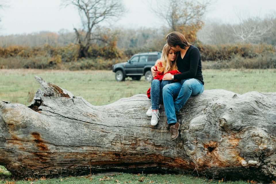 Mother And Daughter Sitting On Tree Log
