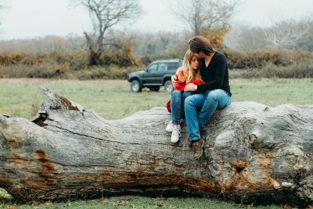 Mother And Daughter Sitting On Tree Log