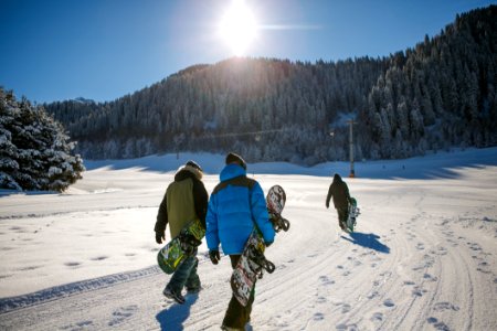 Three Person Holding Bubble Jacket Carrying Snowboards photo