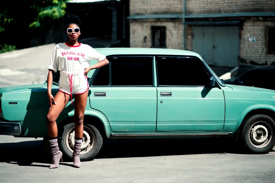 Woman Standing In Front Of Teal Sedan