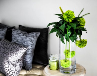 Clear Glass Vase With Green Flowers On Brown Wooden End Table photo