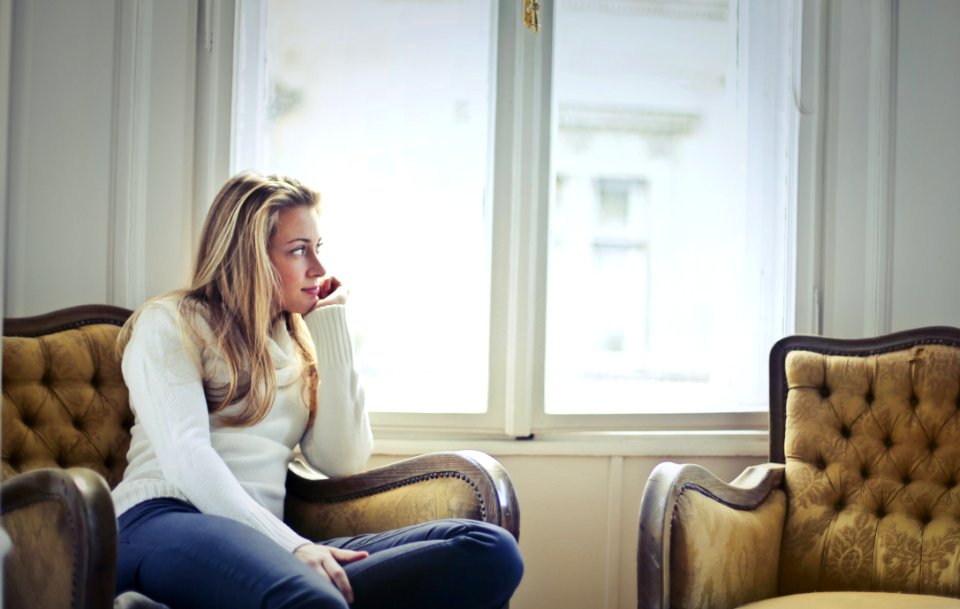 Photography Of Woman Sitting On Chair Near Window