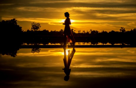 Silhouette Of Man Standing On Lake At Sunset photo