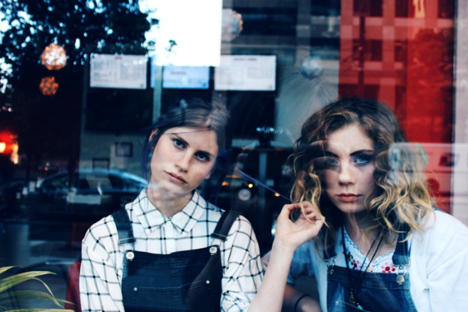 2 Woman In Blue Overalls Sitting Inside Store During Daytim
