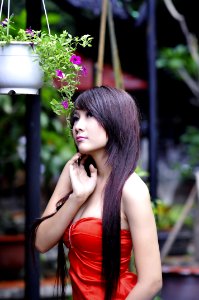 Woman Wearing Red Sweet Heart Neckline Dress Standing Near Hanging Flower Vase photo