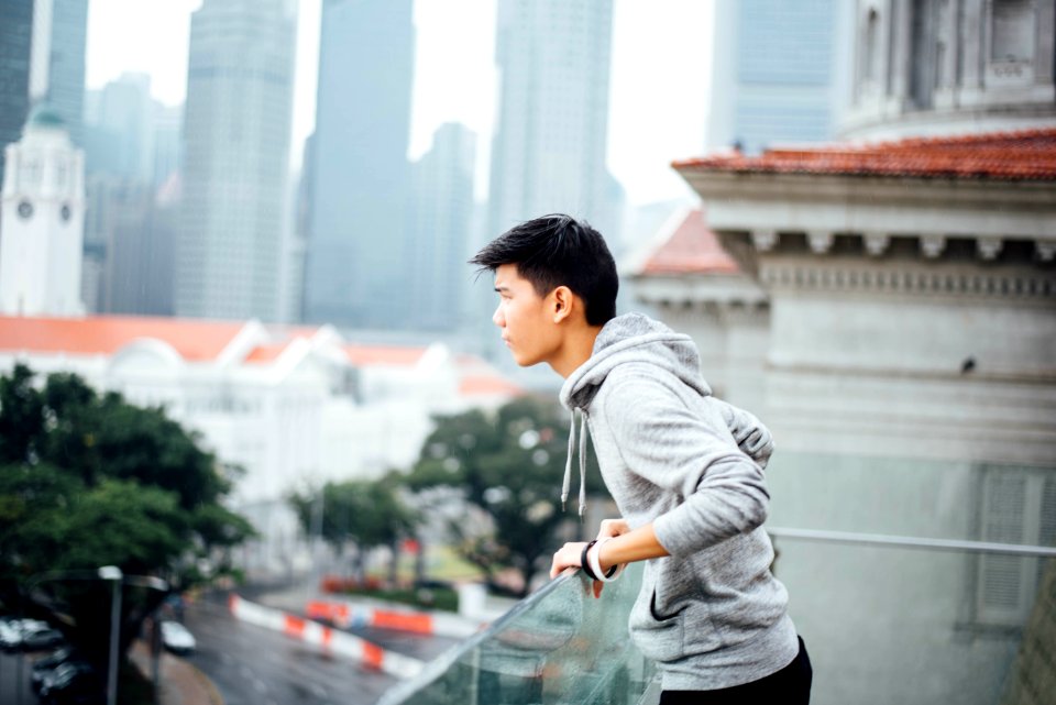Man Wearing Grey Pullover Jacket On A Building In The City During Dayitme