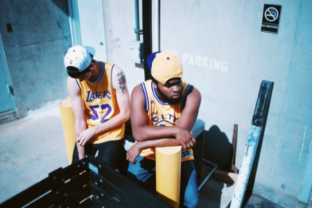Man Wearing Yellow La Lakers Jersey Sitting Next To Man Wearing Yellow Basketball Jersey