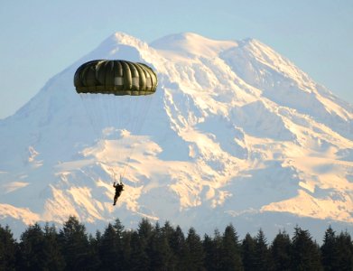 Man Flying On Parachute Near Green Trees photo