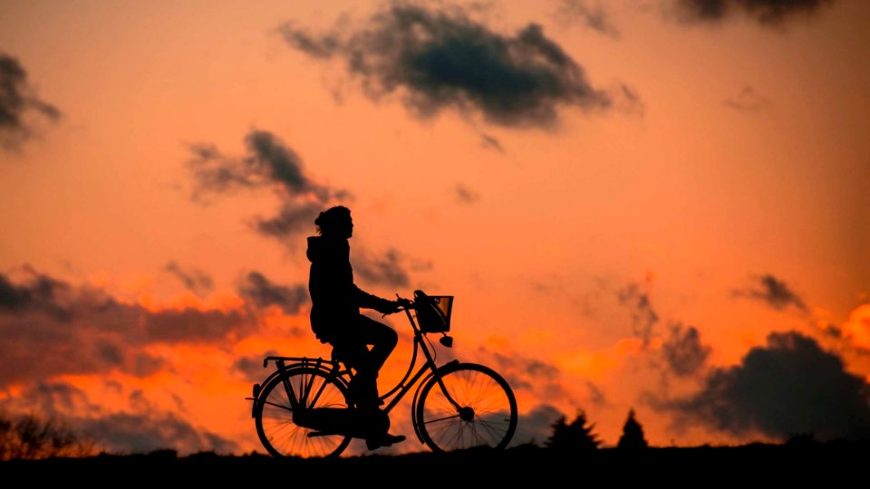 Silhouette Of Person Riding A Bike During Sunset photo