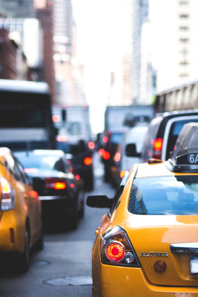 Yellow Altima Taxi Surrounded By Vehicles During Daytime