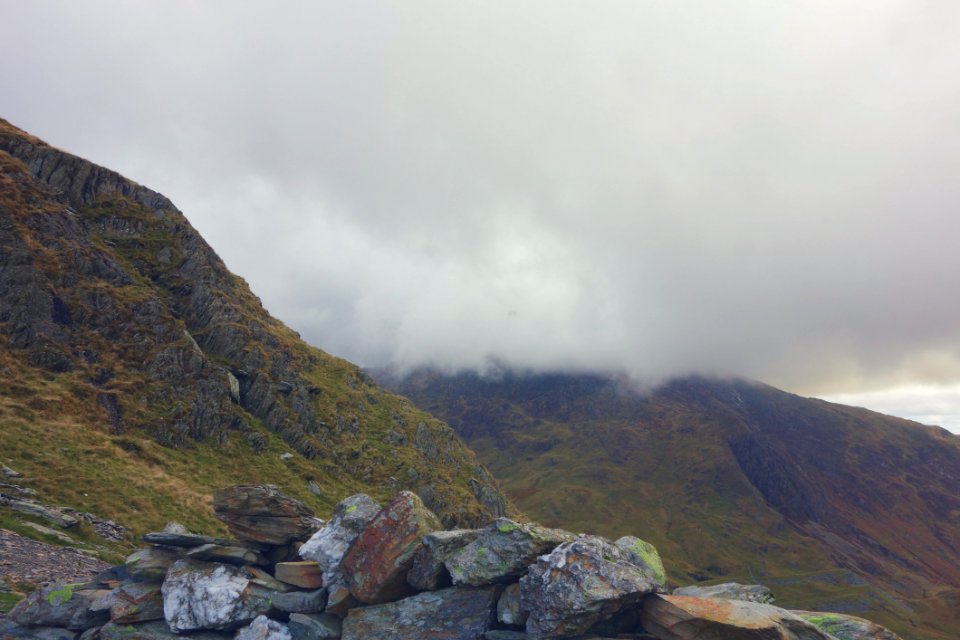 Gray And Brown Rocks Green Lush Mountains And White Clouds In Background