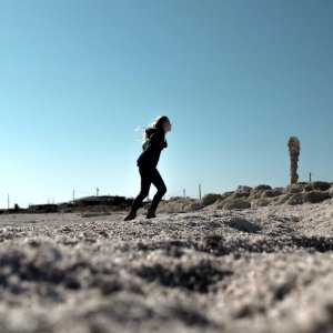 Woman In Black Hoodie And Skinny Jeans In Sandy Field