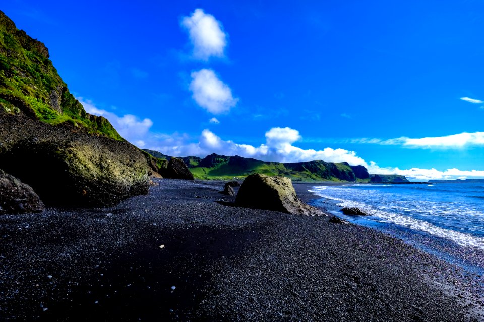 Rocky Beach Against Green Cliffs