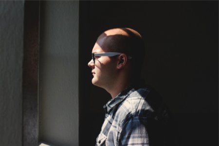Man Standing Looking Straight Forward Through The Window
