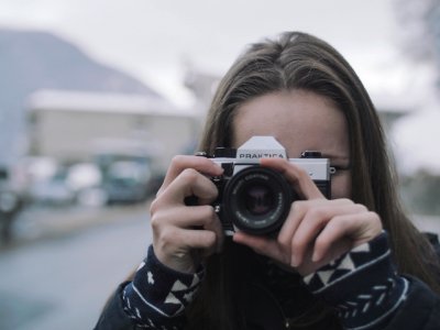 Woman Wearing White And Black Coat Holding Black And Gray Digital Camera photo