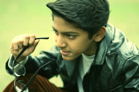Boy Holding Glasses With Serious Expression