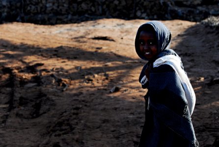 Smiling Child In Black Dress Shirt Walking On Brown Sand During Daytime photo