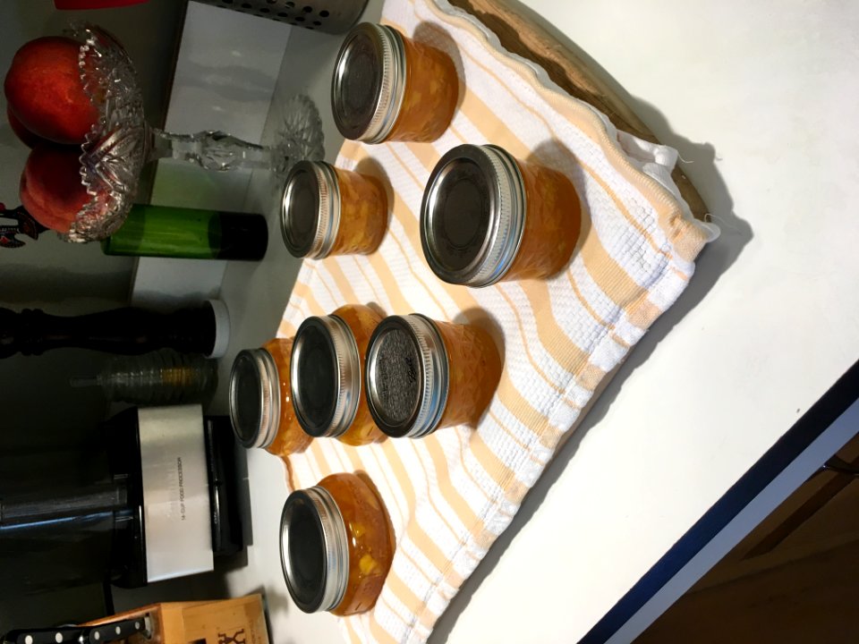 Peach Jam Cooling On Wooden Cutting Board Covered With Kitchen Towel