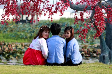Two Girls And A Man Sitting Under A Tree