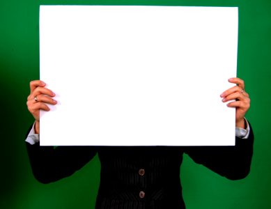Person In A Black Coat Holding White Rectangular Board