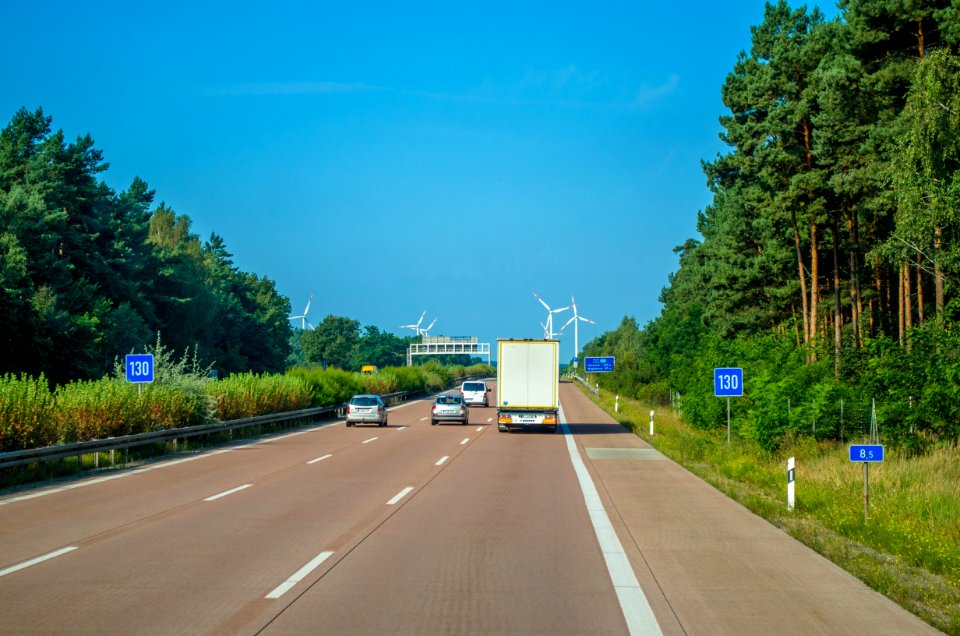 Vehicle Driving On Freeway Towards Wind Turbines