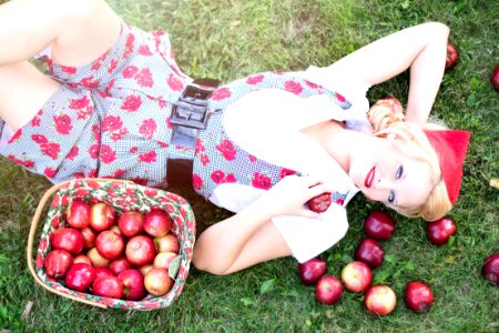 Woman In Gray And White Rose Print Onesies Laying On Grass Beside Red Apple Fruits