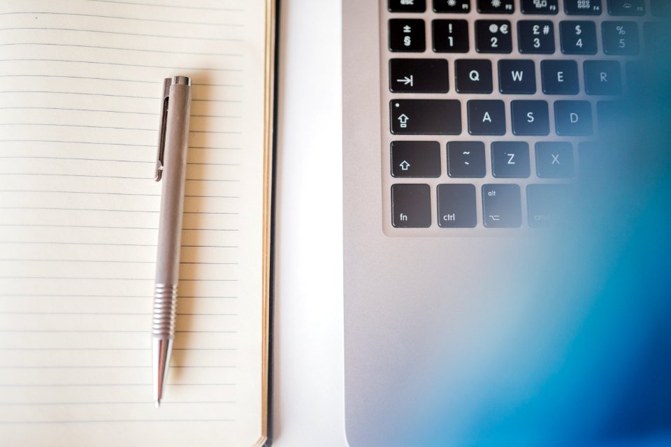 Grey Pen In White Lined Paper Beside Grey Laptop Computer photo