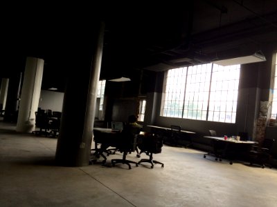 Person Sitting At Office Desk In Warehouse By Pillar photo