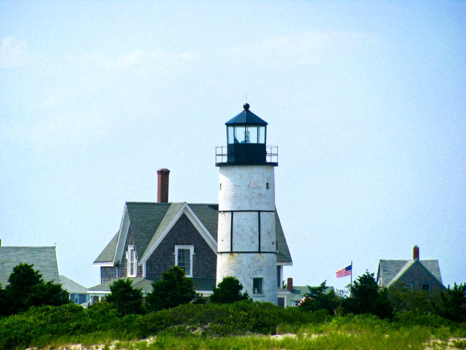 Lighthouse By Home With American Flag