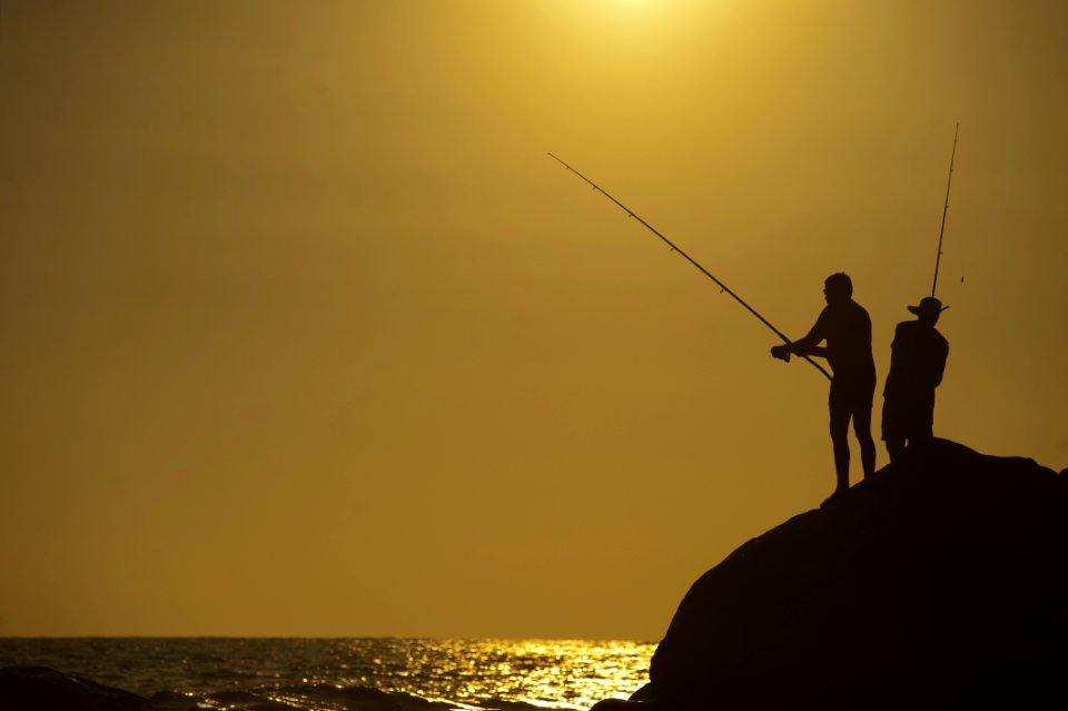 Fishers On A Rock Beside The Sea
