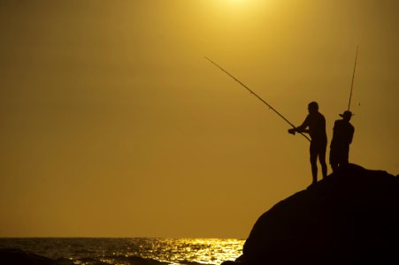 Fishers On A Rock Beside The Sea