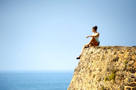 Woman Sitting On Rock By Sea photo