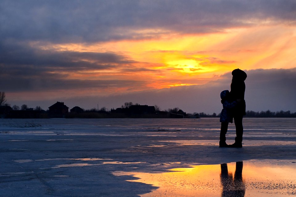 Mother And Child By Frozen Lake At Sunset