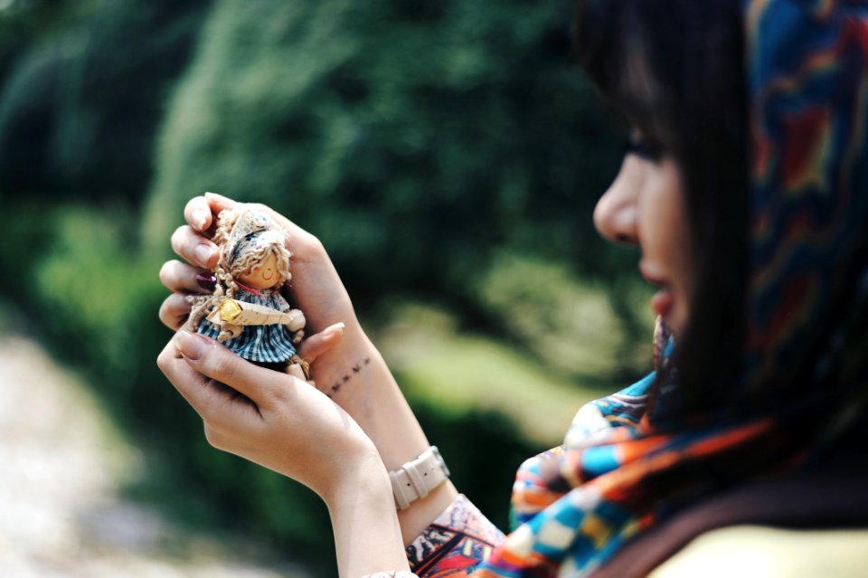 Woman Holding A Tiny Doll And Looking At It